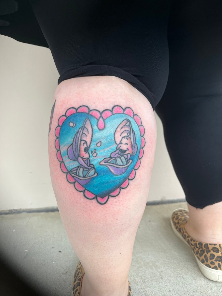 Photograph of a freshly done tattoo on a calf. Tattoo is of baby oysters with a colorful blue background framed within a heart shape